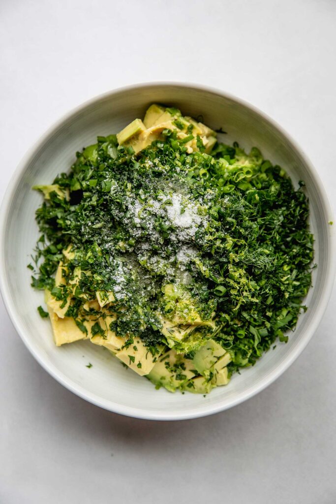 Avocado, herbs, lime and salt in a bowl.