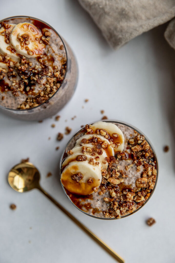Top down view of banana nut chia seed pudding topped with banana slices, date syrup and flaky salt.