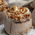 Close up of a jar of banana nut chia pudding layered with pecan crumble and date syrup.