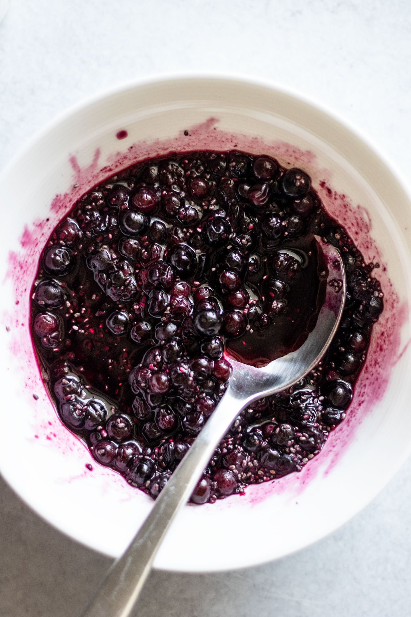 Thawed frozen blueberries being mashed together in a bowl with some chia seeds.