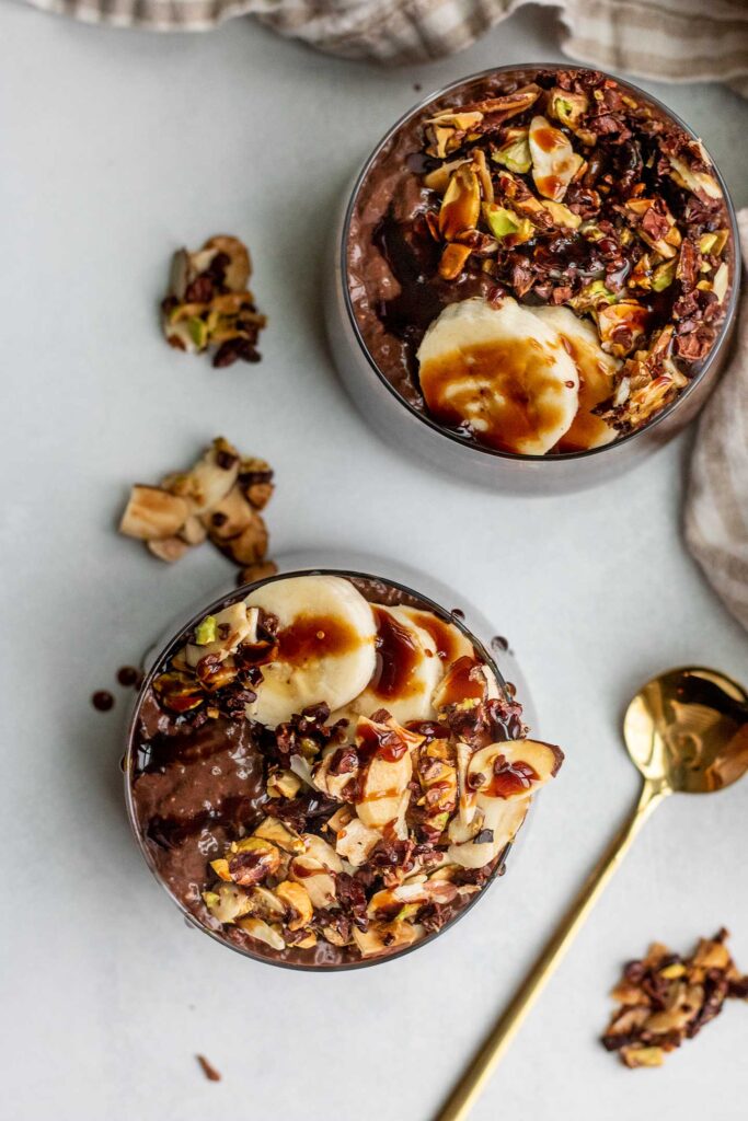 Top down view of two jars of chocolate chia pudding topped with banana and lemon nut granola.