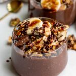 Close up of two cups of chia pudding topped with nutty granola.