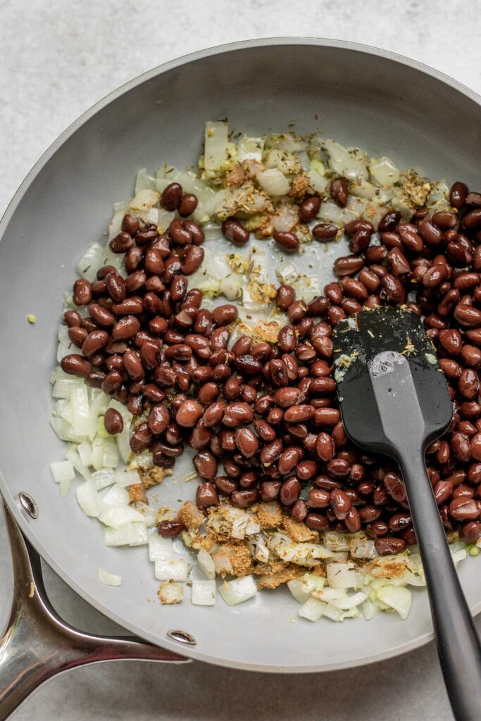 Stirring in the black beans into the onion mixture.