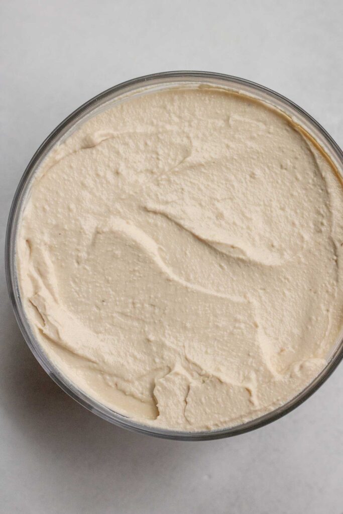 Blended cream cheese added to a glass container.