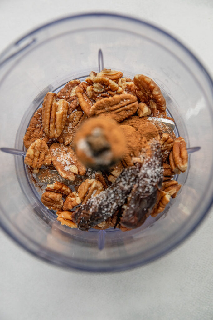Pecans, dates and cinnamon in a mini food processor.