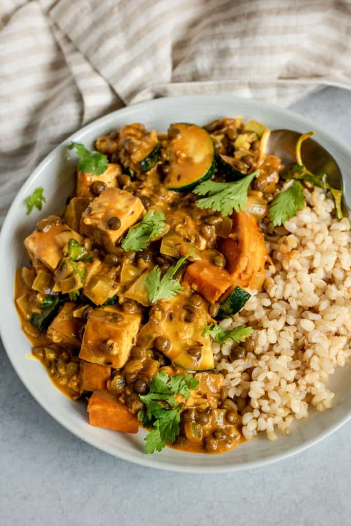 Plate of stew paired with rice and topped with cilantro.