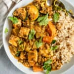 Tofu stew in a bowl with rice and fresh cilantro.