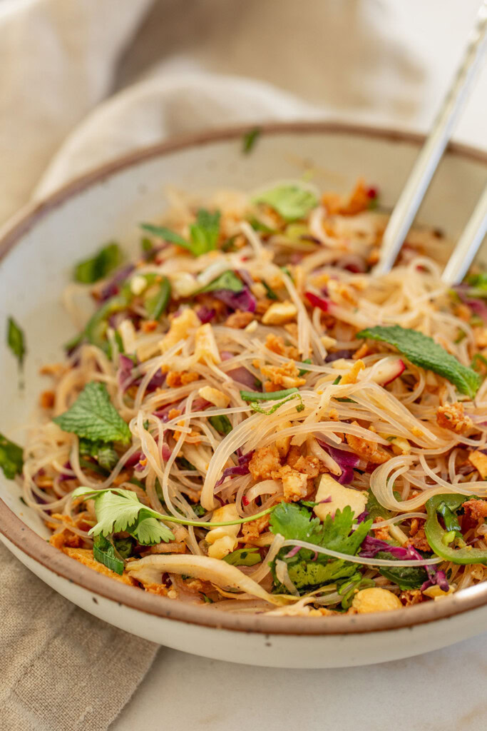 Mixing the bowl of noodles together with the veggies and crunchy cashews.