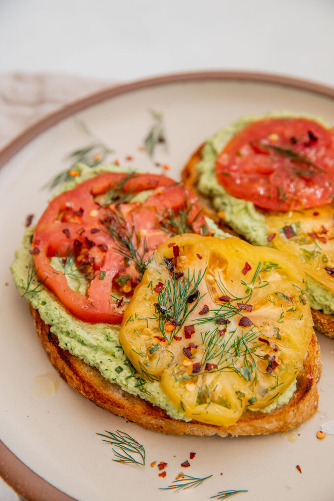 Close up of toast topped with edamame spread and marinated tomatoes.