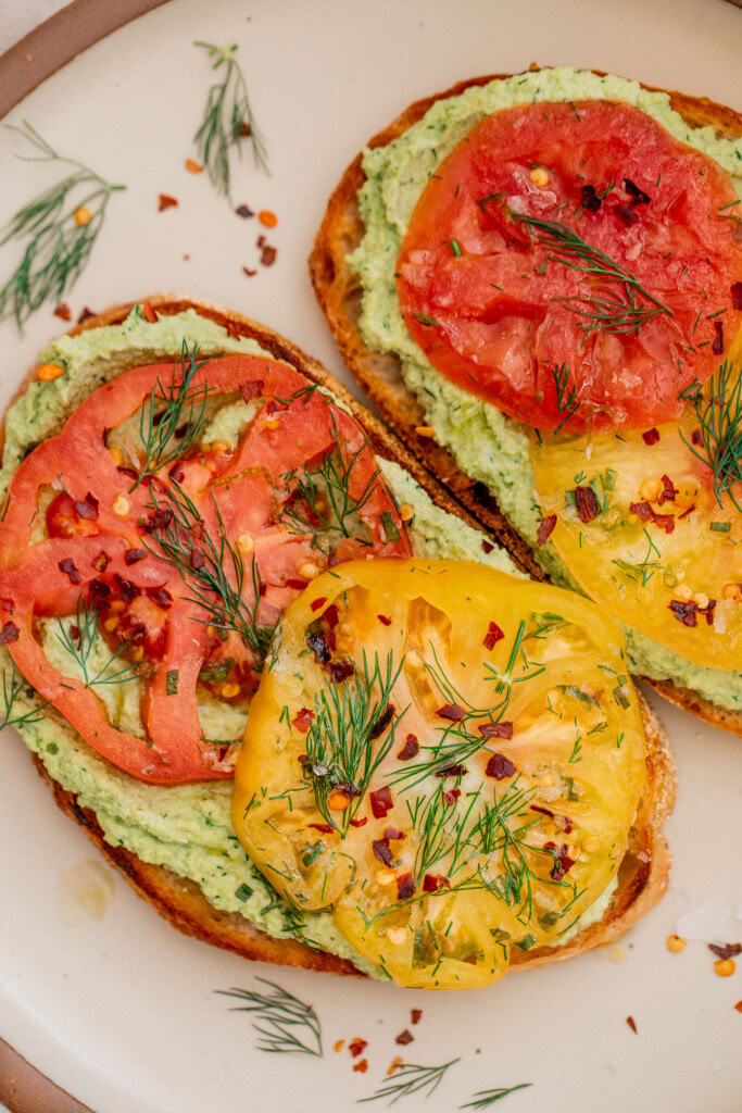 Toast topped with edamame spread and sliced marinated tomatoes.