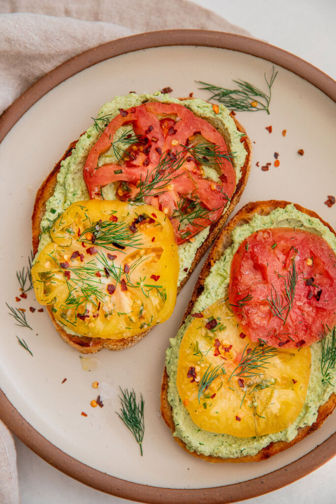 Top down view of 2 pieces of toast topped with edamame and marinated tomatoes.