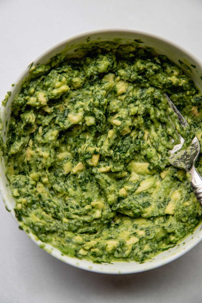 Mashed avocado and herbs in a bowl.