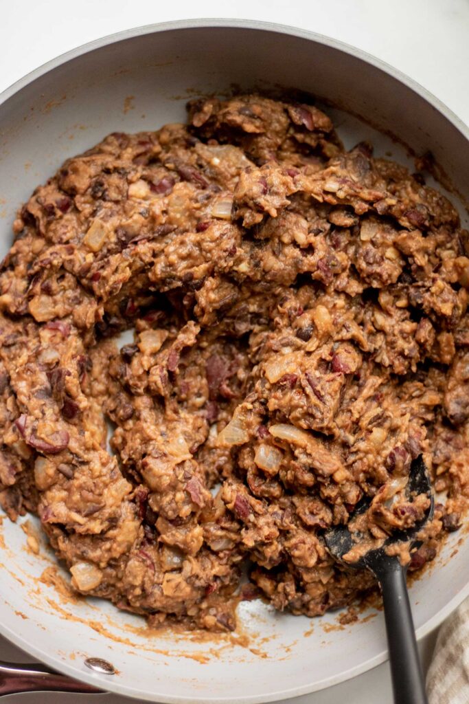 Mashed and thickened black beans in a pan.