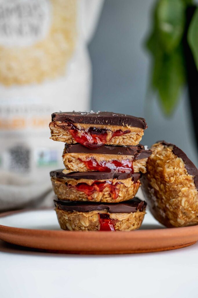 Plate stacked with oat cups stuffed with peanut butter and jelly with a bag of One Degree Organic Oats in the background.