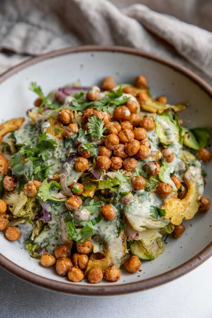 Roasted squash and brussels sprout salad topped with chickpeas and creamy dressing.