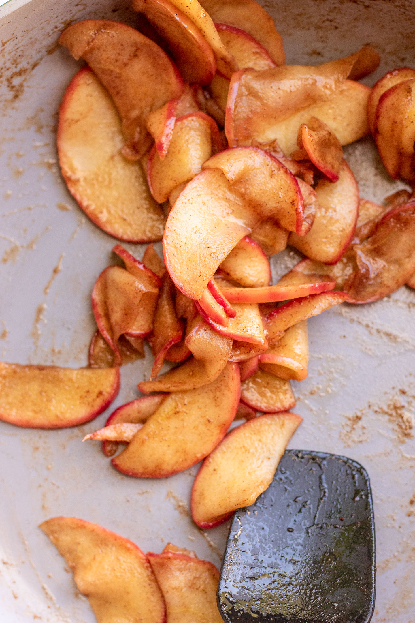 Sauteed apples being stirred in a pan with a spatula.
