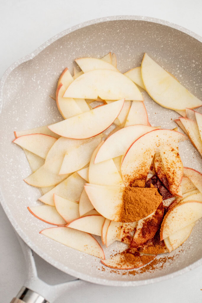 Sliced apples in a pan with cinnamon and agave syrup.