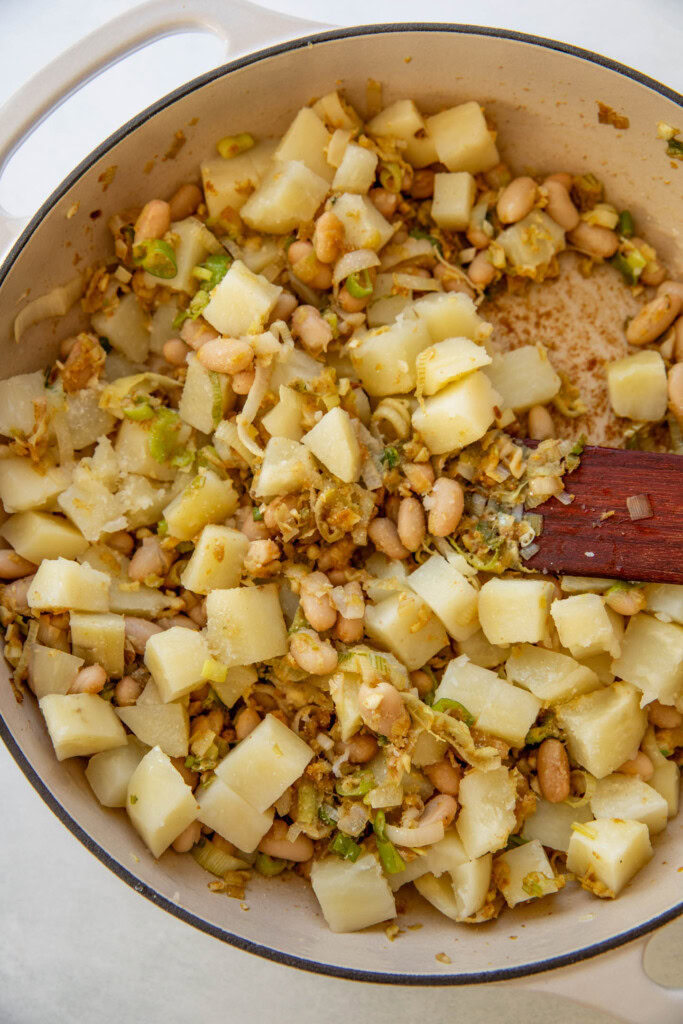Mashing the beans and potatoes together in a pan with the cooked leeks.