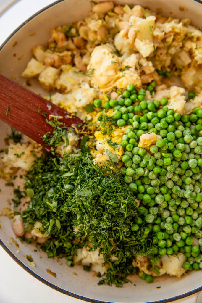 Folding in the peas and herbs into the potato mixture.