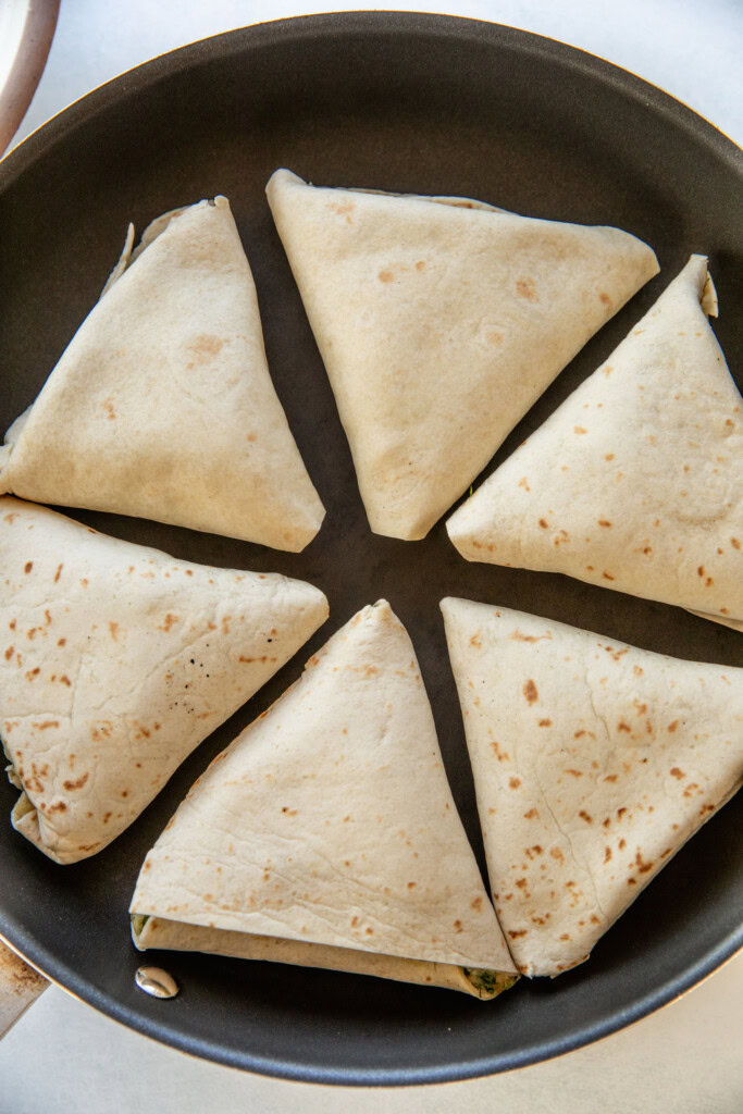 6 folded triangle wraps in a pan to toast until golden.