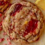 Close up of a cookie with pools of strawberry jam on top.