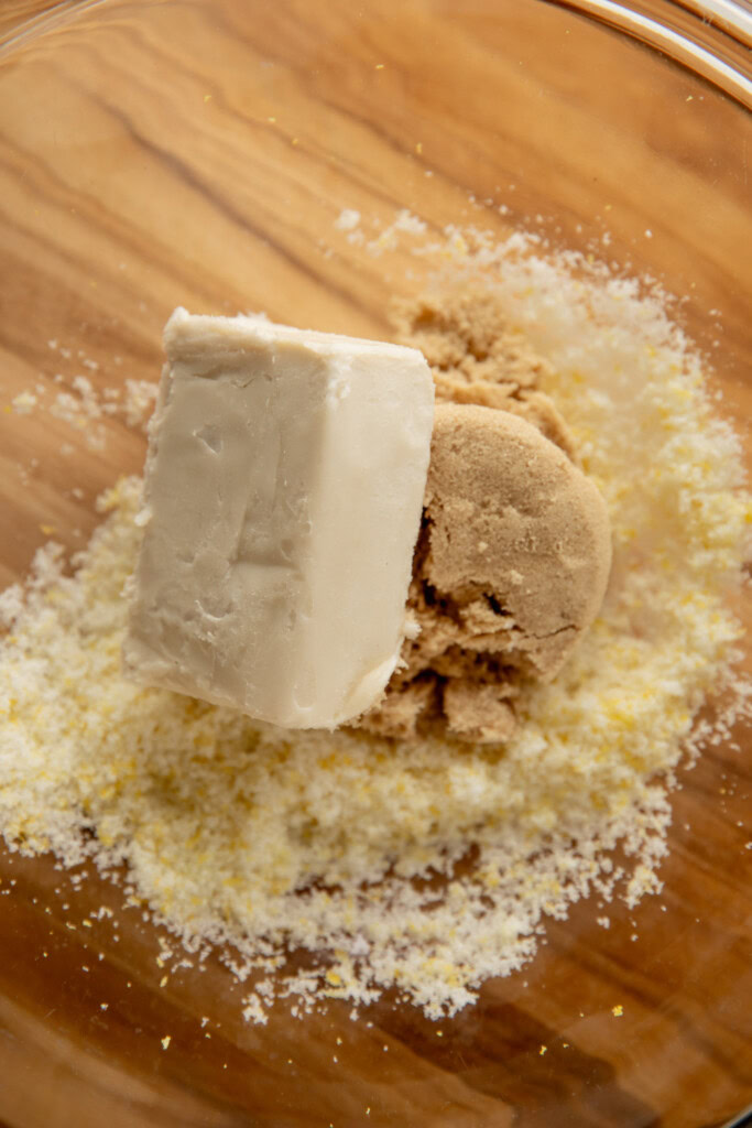 A block of butter and light brown sugar in a bowl with the lemon sugar.