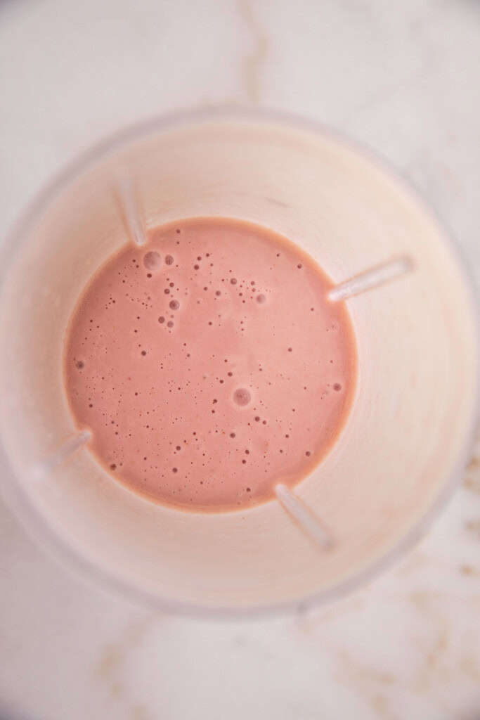 Blended strawberry milk in a blender cup.
