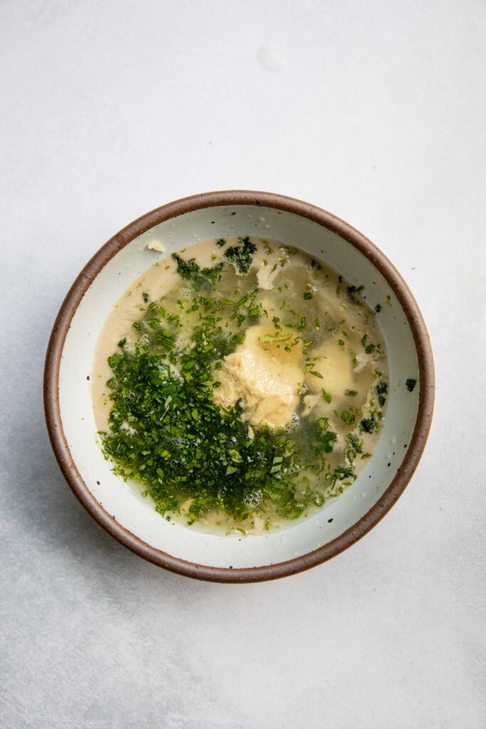 Mixing the dressing together in a bowl.