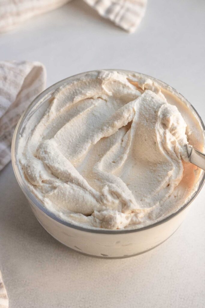 Creamy tofu cream cheese in a container with a knife tucked into the side.