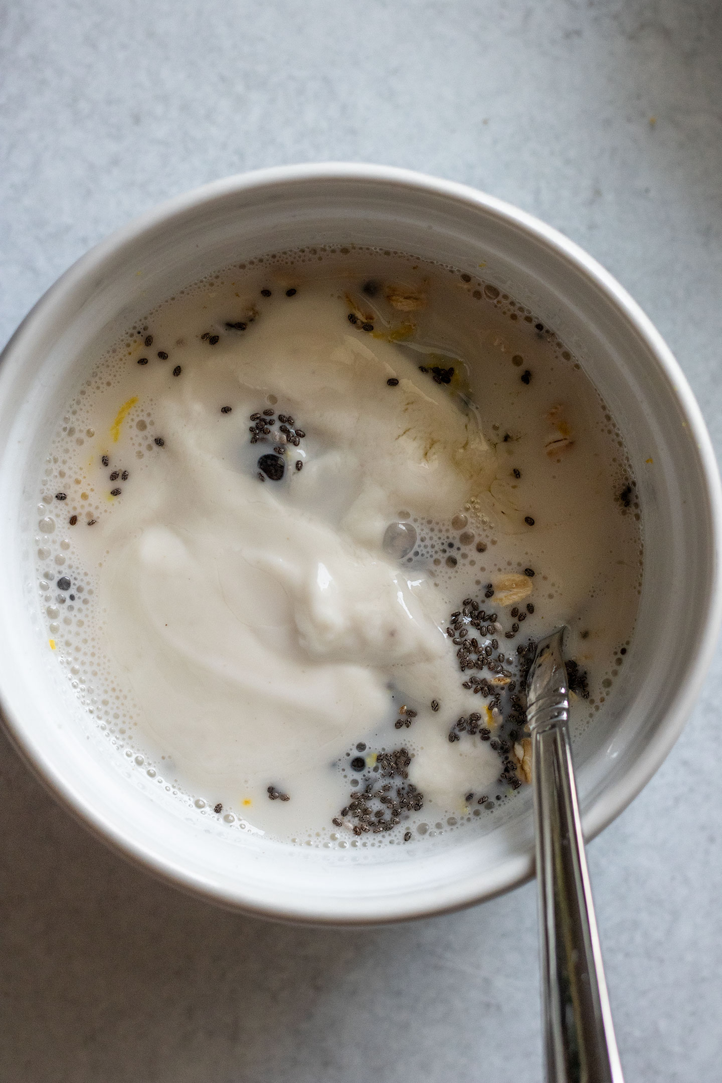 Mixing the plant based milk and yogurt into the oats and chia seeds.